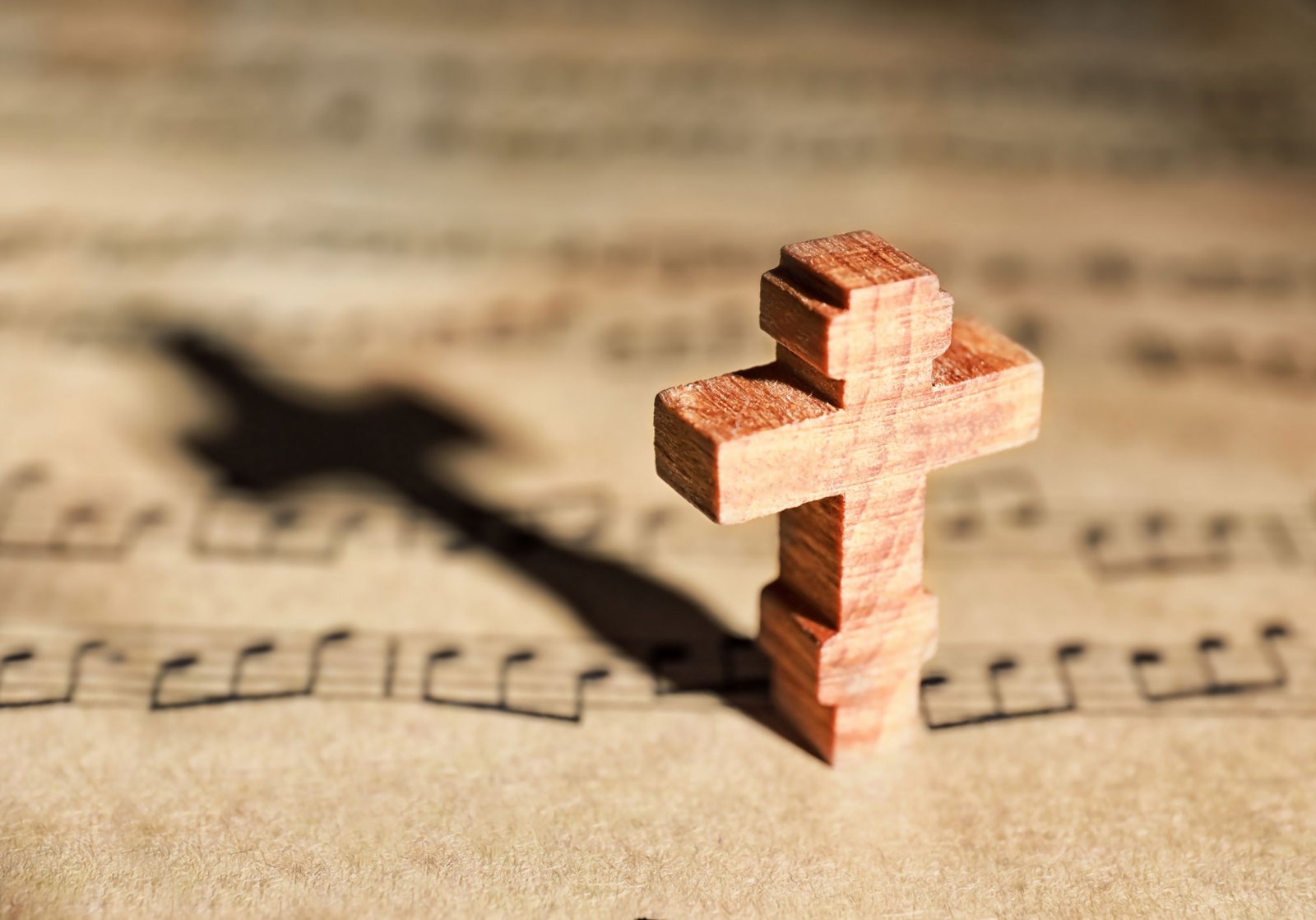 Wooden cross resting on sheet music